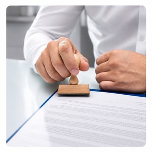 A person using a wooden rubber stamp to mark an official document