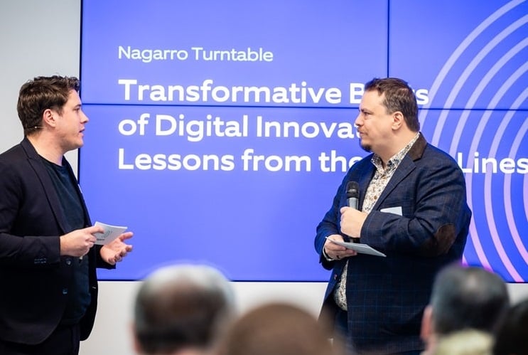 Two male speakers talking about digital innovation in front of an audience