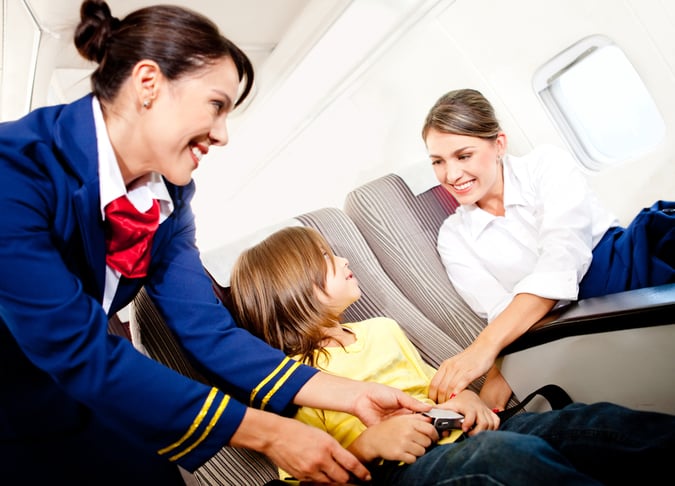 Air hostess helping a kid to fasten his seatbelt