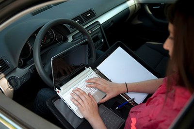 A women using her laptop inside her car.