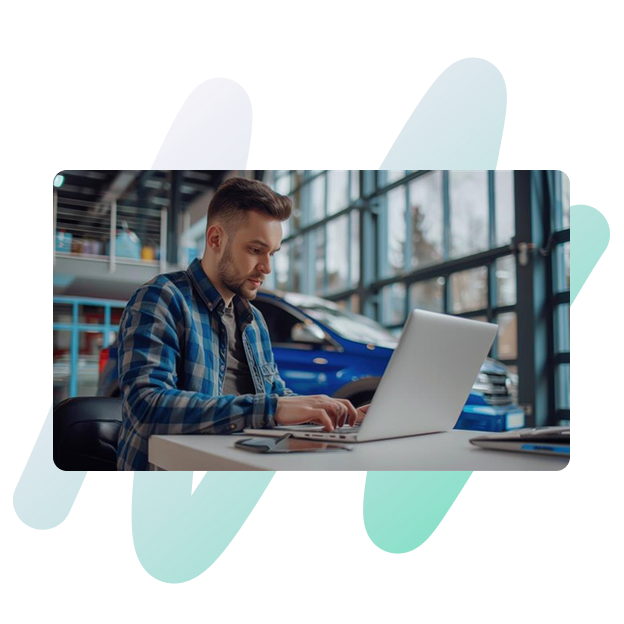 A man working on his laptop in an automotive setting