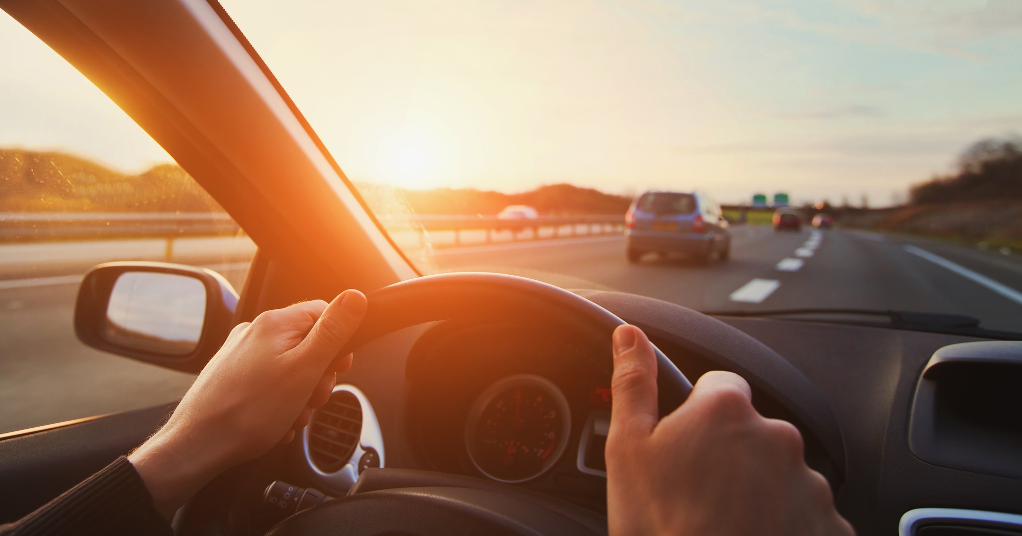 Man holding a car's steering wheel driving on the road