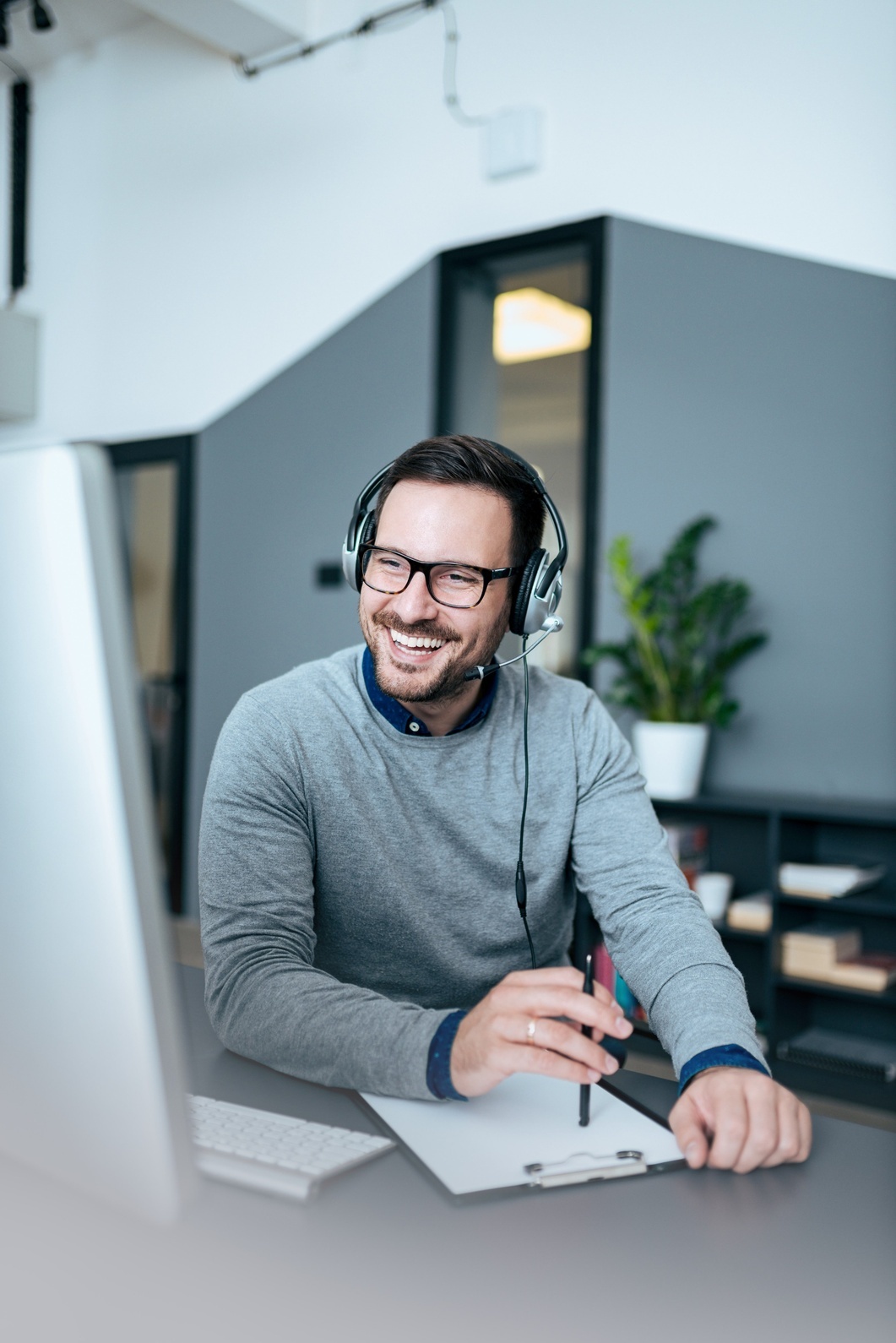 A person wearing the headset and using computer in the office.