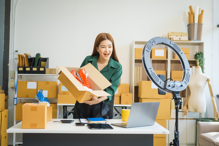 A woman holding a shoe box and showing it on a live stream on social media platforms.