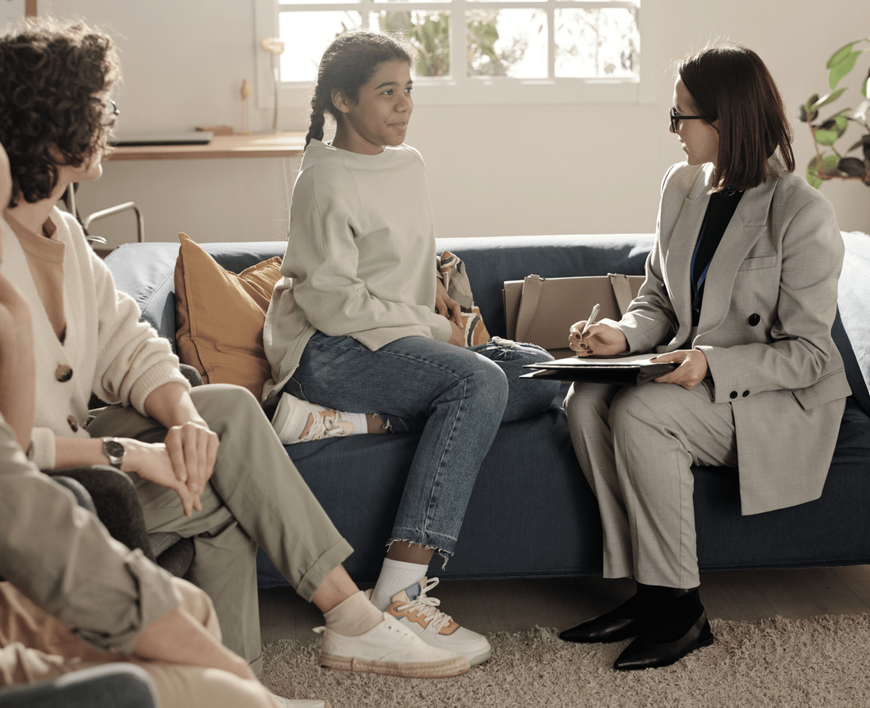 A group of people sitting on couch and discussing with social caseworker.