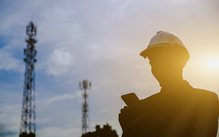 Man looking at his mobile with telecom towers in the background